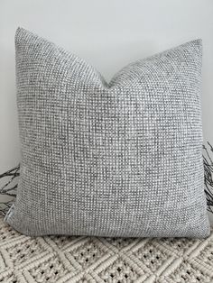 a gray and white pillow sitting on top of a bed