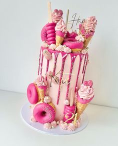 a pink birthday cake with donuts and sprinkles on the top tier