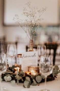 the table is set with wine glasses, candles and greenery for an elegant centerpiece