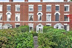 an old brick building with many windows and bushes