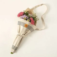 a bouquet of flowers is wrapped in a canvas bag on a white surface with a ribbon around it