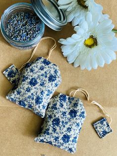 two blue and white flowered tea bags with tags on them next to some flowers