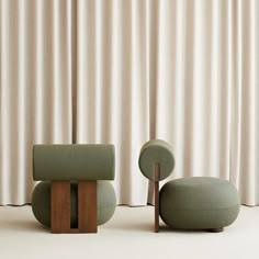 two green chairs sitting next to each other in front of a curtain