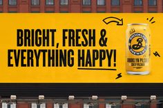 a yellow and black advertisement on the side of a building with an image of a can of beer