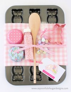 an assortment of baking utensils in a muffin tin with pink gingham