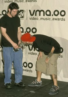 two men standing next to each other with a red object in their hand and one holding it up