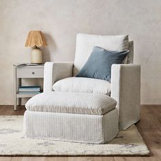 a chair and ottoman in a room with a lamp on the side table next to it