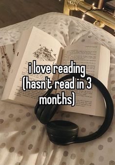 an open book sitting on top of a bed with headphones in front of it