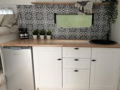 a kitchen with white cabinets and black and white tile backsplash