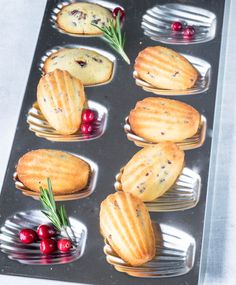 some food is sitting in a muffin tin on a table with cranberries and rosemary