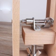 a close up of a metal clamp on top of a wooden shelf with screws