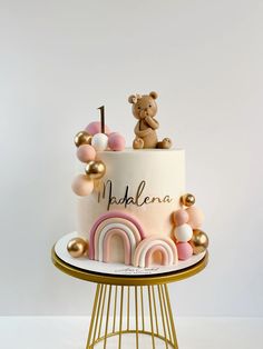 a pink and gold cake with a teddy bear on top