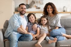 a family sitting on a couch in the living room with their arms around each other