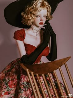 a woman in a black hat and dress sitting on a chair