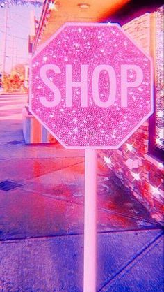 a pink stop sign sitting on the side of a road next to a store front