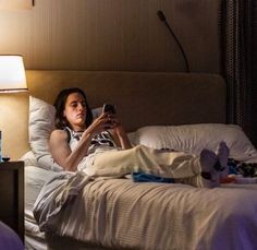 a woman laying in bed while looking at her cell phone