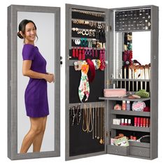 a woman in a purple dress is standing next to a jewelry cabinet with an open door