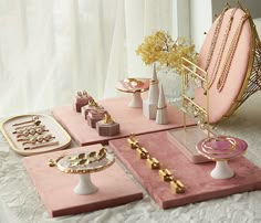 pink and gold jewelry on display in front of a white window with sheer drapes