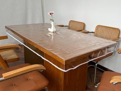 a wooden table with chairs around it and a vase with a flower on the top