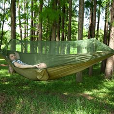 a man laying in a green hammock with trees in the backgroud