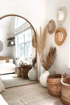 a living room filled with lots of white furniture and baskets on the floor next to a window