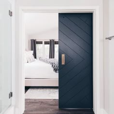 an open door leading to a bedroom with a white bed and black chevron design