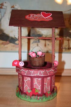 a small wooden bird feeder with flowers in it's center and a heart on the top