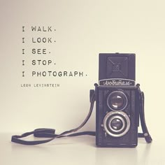 an old camera sitting on top of a table next to a wall with words above it