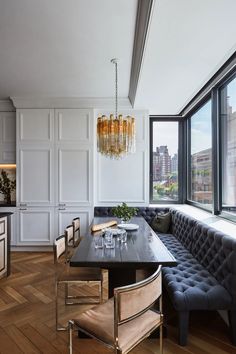 a dining room table with chairs and a bench in front of a window overlooking the city