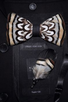 Feather bow tie in warm tones of brown, black, and cream with matching feather lapel pin, styled on a textured black fabric background with minimalist white text.