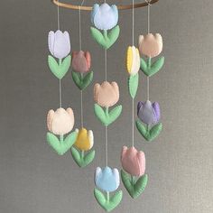 a mobile with flowers hanging from it's side on a table next to a wall