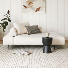 a living room with a white couch and coffee table in front of a painting on the wall