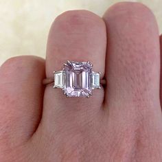 A delicate gemstone ring featuring a lively, emerald-cut, natural kunzite. The center stone is beautifully saturated with a pink hue and weighs approximately 2.88 carats. The kunzite is set in prongs and flanked by two trapezoid-cut diamonds on each shoulder. This ring is handcrafted in platinum.
The total diamond weight of the side diamonds is 0.40 carats.
The approximate measurements of the center stone are 8.97mm x 7.00mm.
This ring can be resized to any finger size at no additional cost.
If Kunzite Engagement Ring, Kunzite Ring, Estate Diamond Jewelry, Future Engagement Rings, Perfect Engagement Ring, Unique Engagement Rings, Gemstone Ring, Emerald Cut, Gemstone Colors