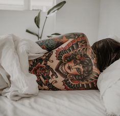 a woman laying on top of a bed covered in tattoos