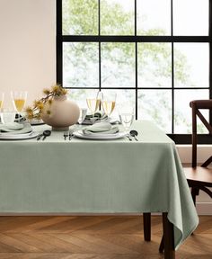 the table is set for two with glasses and plates on it, near a large window