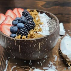 a bowl filled with cereal and fruit on top of a wooden table next to coconuts