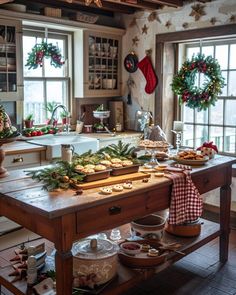 a wooden table topped with lots of food and christmas wreaths on top of it