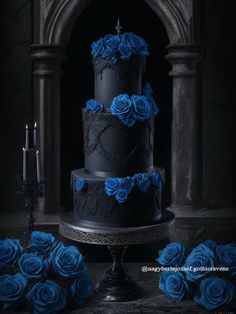 a three tiered black cake with blue roses on the side and candles next to it