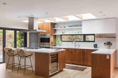 a kitchen with wooden floors and white counter tops next to sliding glass doors that look out onto the backyard