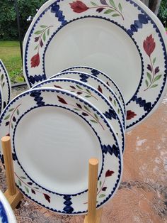 a bunch of plates that are sitting on some wood sticks in front of the grass