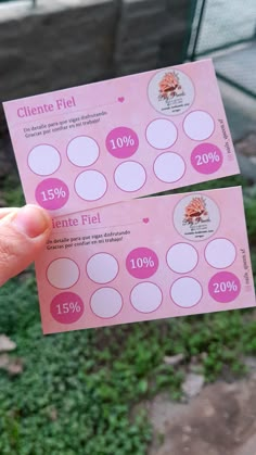 two pink tickets are held up in front of the camera, with white circles on them