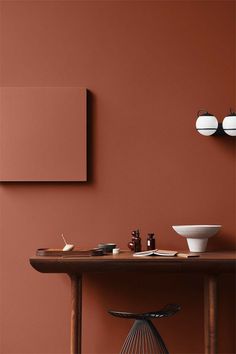 a wooden table topped with white bowls and vases next to a wall painted in red