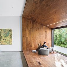 a person sitting on a bean bag chair in front of a window with wood paneling