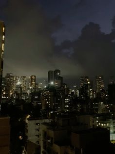 the city skyline is lit up at night with skyscrapers in the foreground and clouds in the background