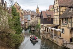 two people in a small boat traveling down a river between old buildings on both sides