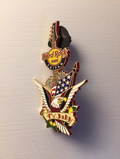 an american flag and eagle lapel pin on a white brick wall with the words hard rock cafe