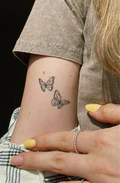 two women with matching tattoos on their backs, one has a butterfly tattoo on her left arm