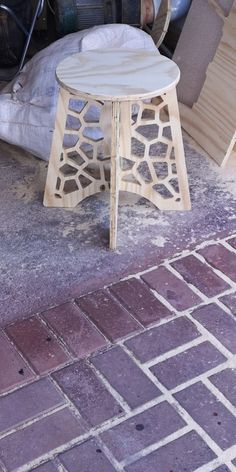 a small wooden table sitting on top of a brick floor next to a pile of furniture