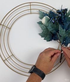 a person is making a wreath out of metal wire and fake flowers on the wall