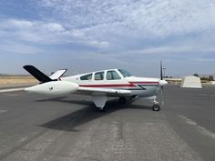 a small white airplane sitting on top of an airport tarmac with no one around it